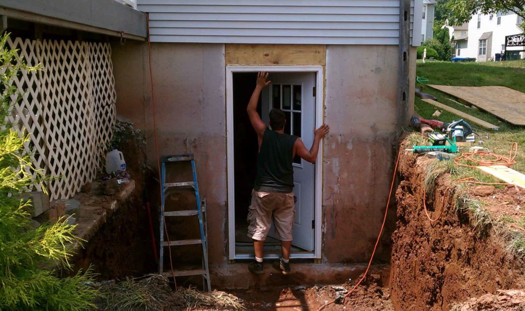 A worker is installing the Cleargress® lightweight door to customer's basement