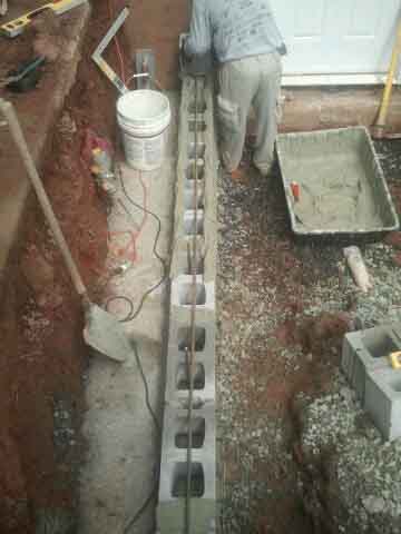 The worker is building on the foudation of basement permentry entrance